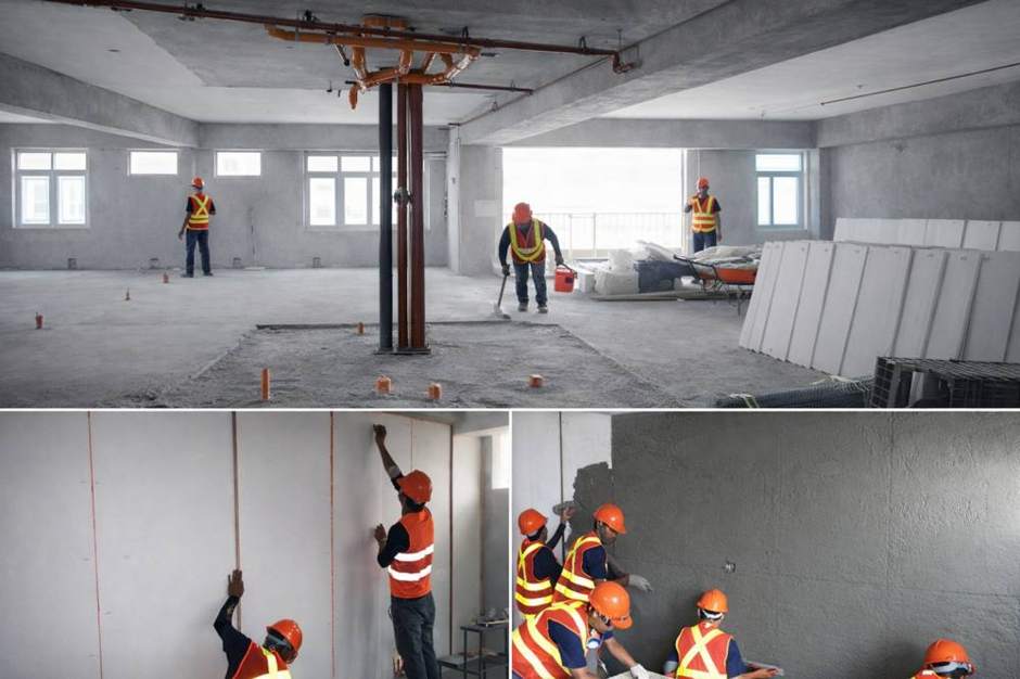 Partition panels staged on a high-rise floor and crews setting and plastering walls